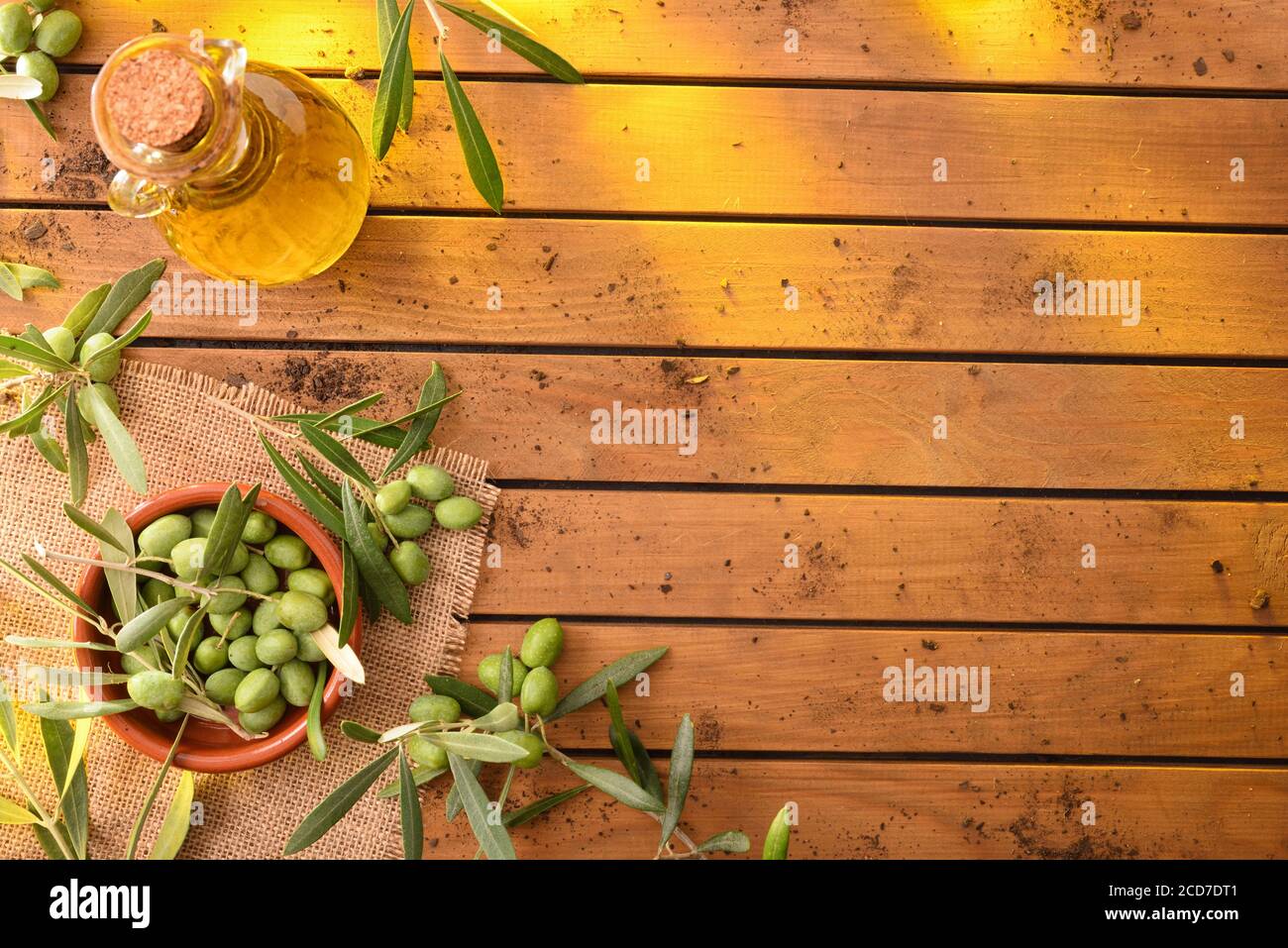 Olivenzweige gefüllt mit Oliven auf Holztisch mit Ölbehälter und Tonbehälter. Olivenernte Konzept für die Olivenherstellung. Draufsicht Stockfoto