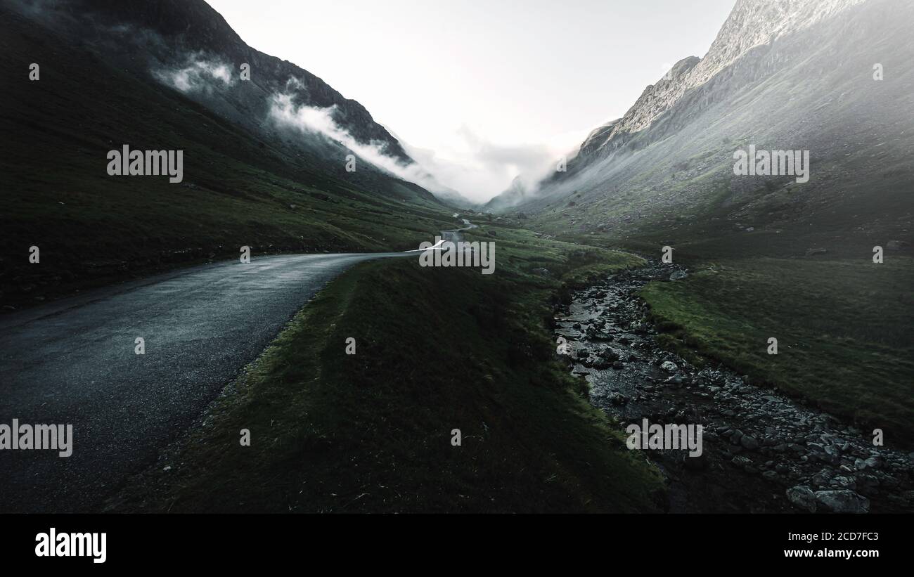 Moody Bild von Honister Pass in Lake District, Cumbria, UK.Nebel im Bergtal mit Landstraße und Bach. Stockfoto