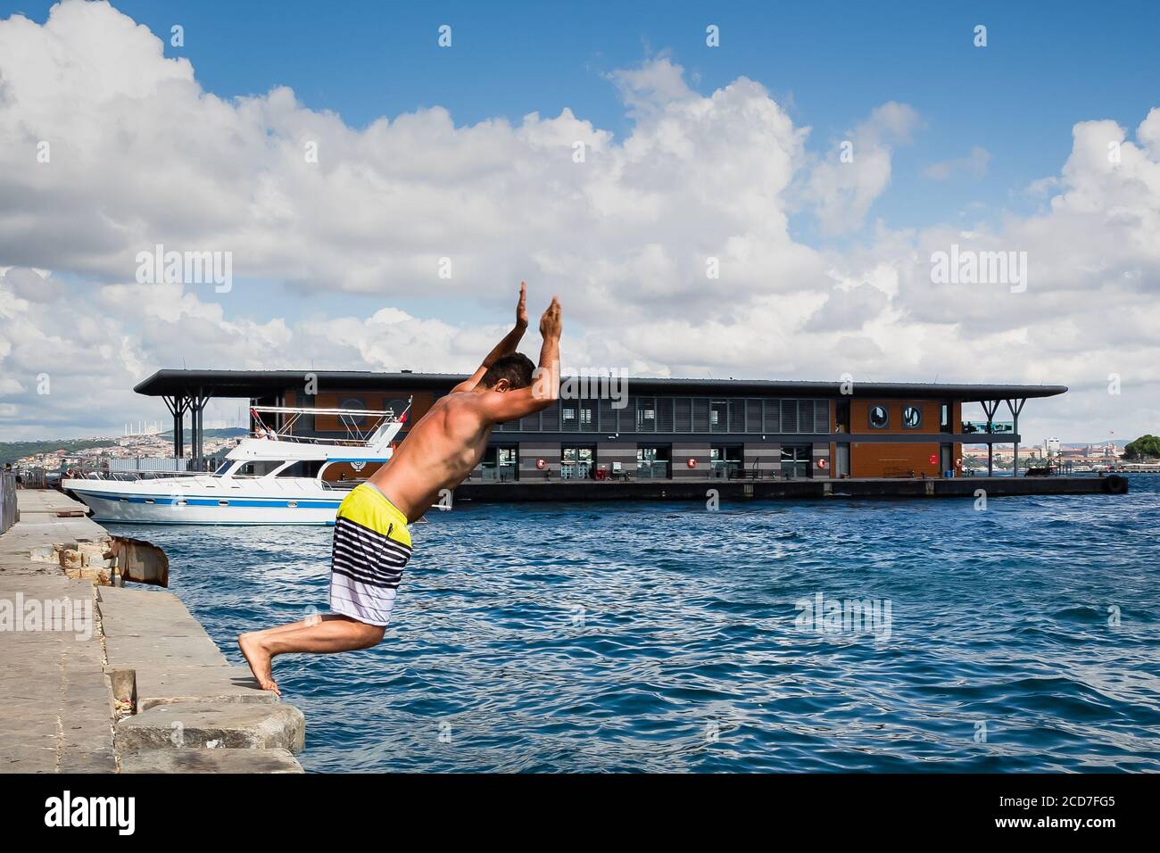 Junger türkischer Mann, der an einem heißen Sommertag vom Pier von Karakoy im Meer springt, das Goldene Horn, Istanbul, Türkei. Stockfoto