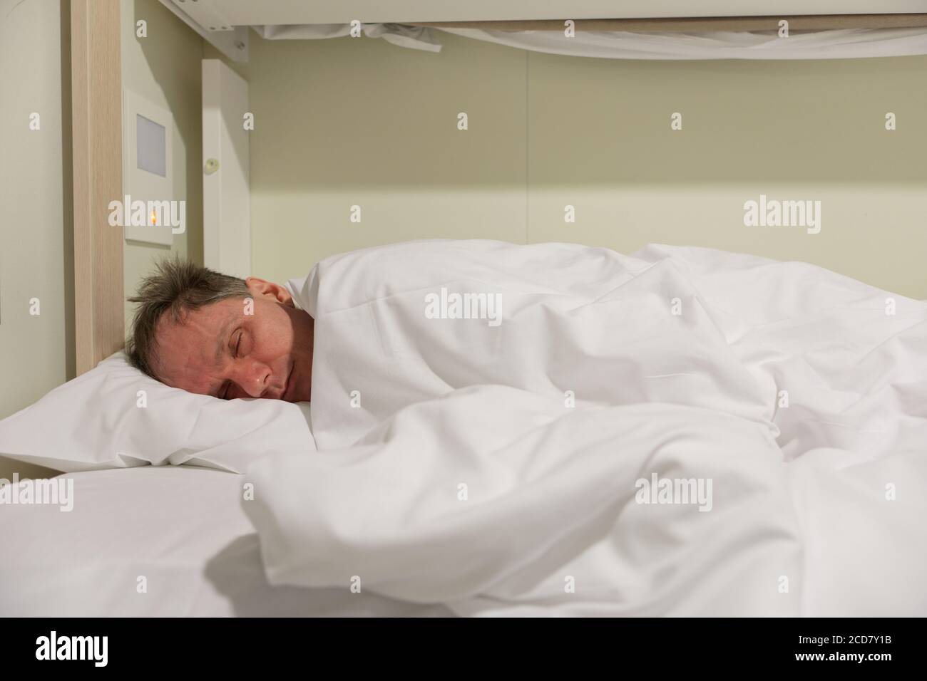 Mann, der auf einem Liegeplatz in einer Kabine einer Kreuzfahrt schläft Versand Stockfoto