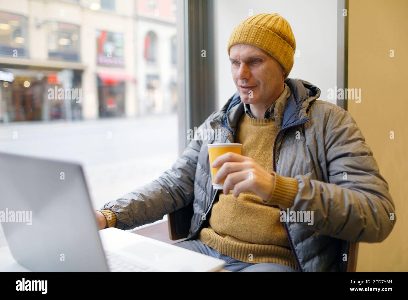 Mann trinkt Kaffee und schaut in seinem Laptop in einem Café in Stockholm, Schweden Stockfoto