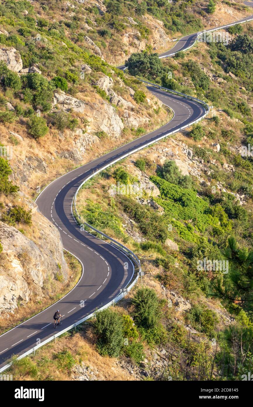 Kurvige Straße bergauf mit kleinen Radfahrer, Sant Pere de Rodes, Costa Brava, Girona, Katalonien, Spanien Stockfoto