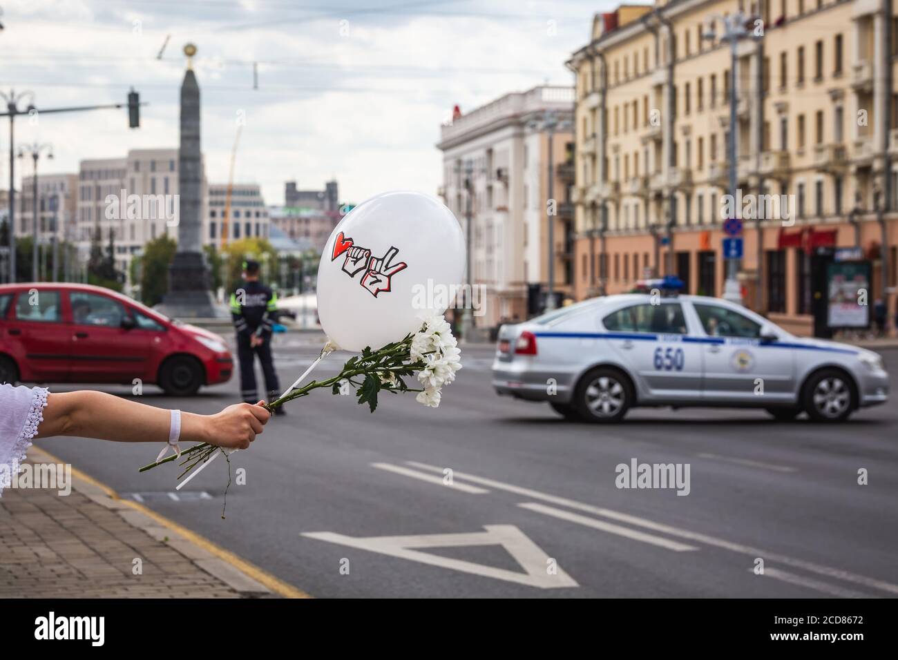 Frauen halten Ballon und Blumen während friedlicher Proteste gegen gestohlene Präsidentschaftswahlen in Minsk, Weißrussland. Polizist und Polizeiauto am Stockfoto