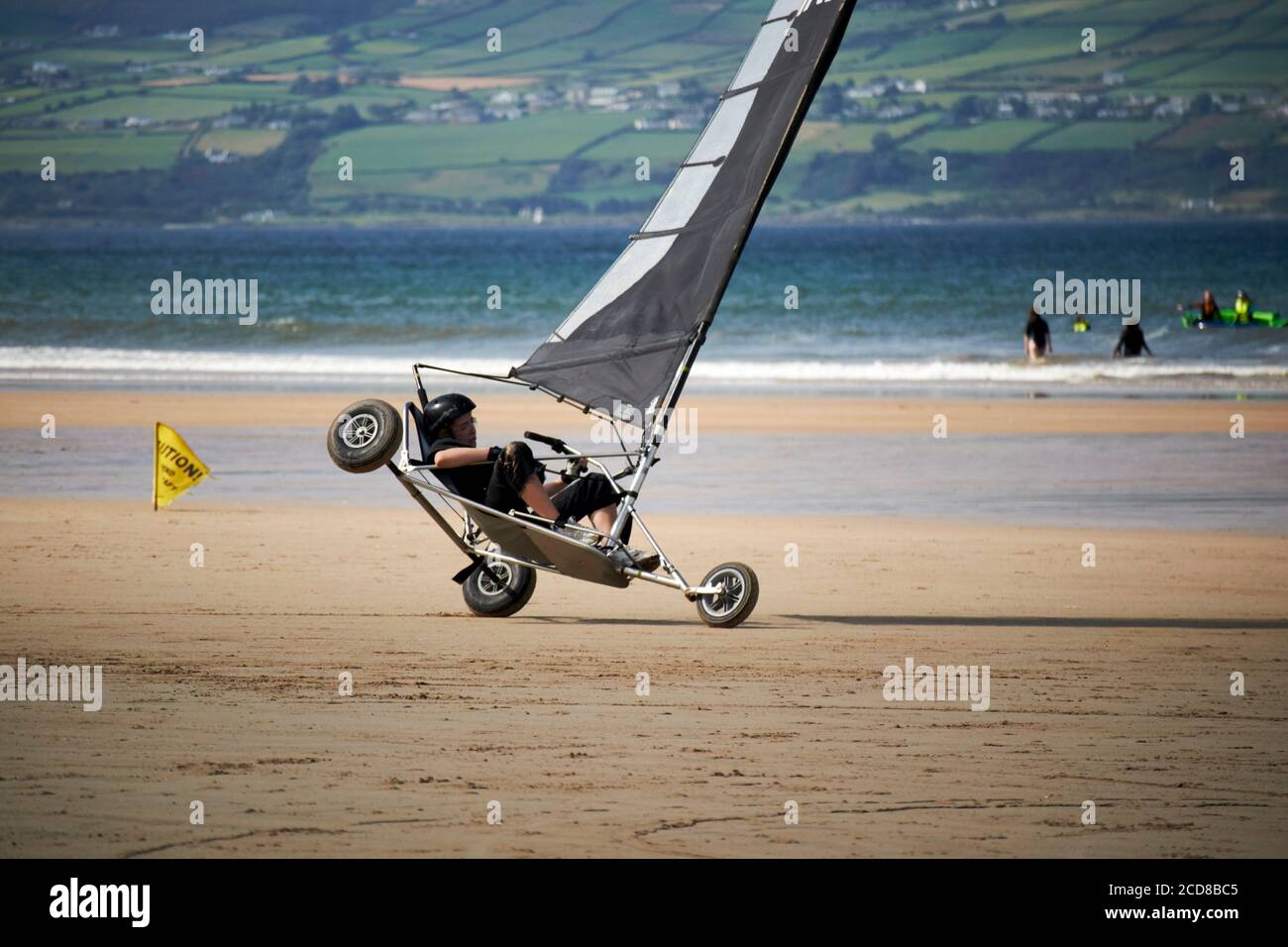 Junge Frau fährt blokart mit Geschwindigkeit kippt über kompakte Land Yachten am strand von benone Nordirland großbritannien Stockfoto