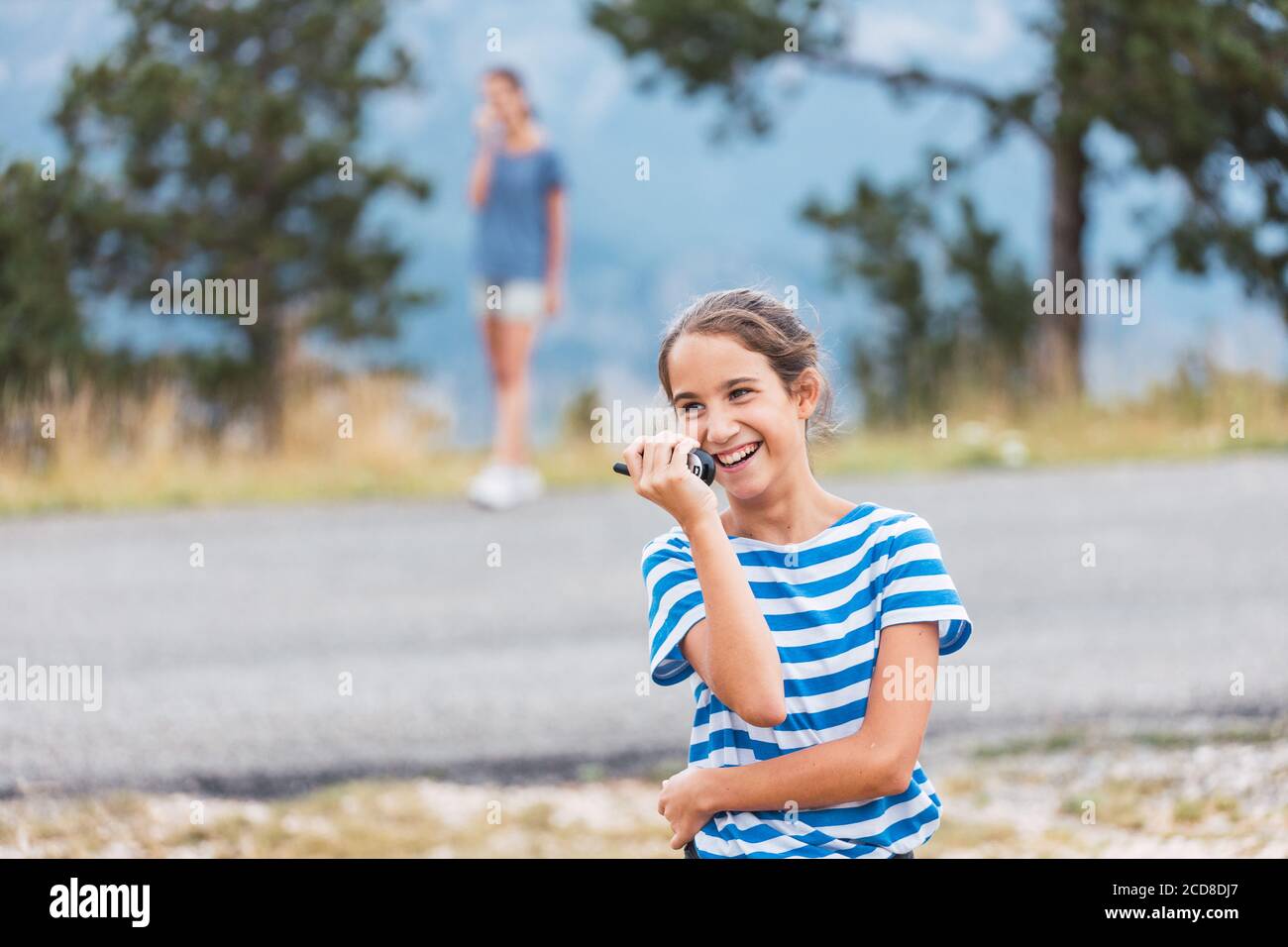 Zwei Mädchen haben Spaß beim Spielen mit Walkie-Talkies während einer Wanderung In den Bergen Stockfoto