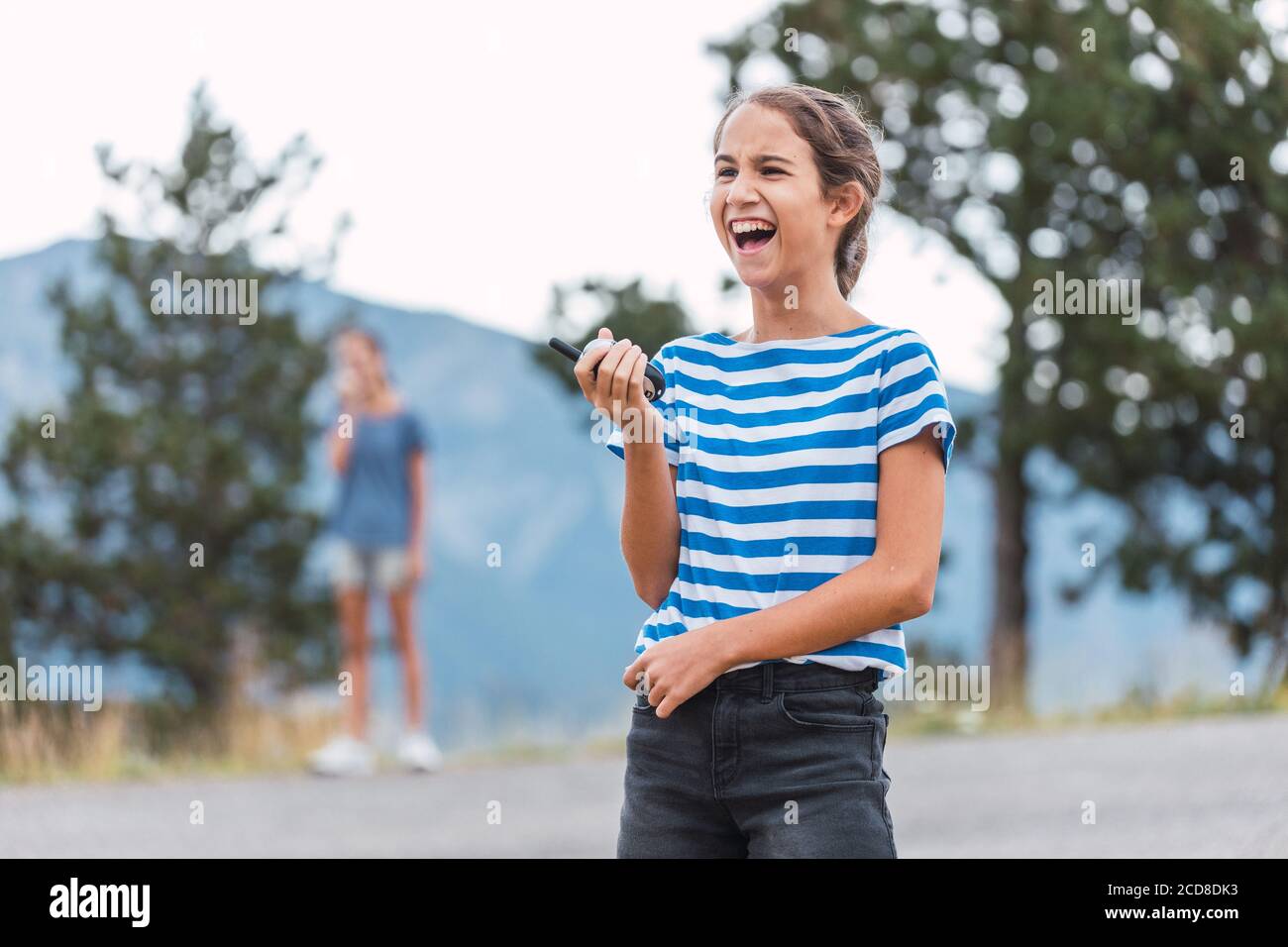 Zwei Schwestern, die im Freien spielen und lachen, kommunizieren durch Walkie-Talkies Stockfoto