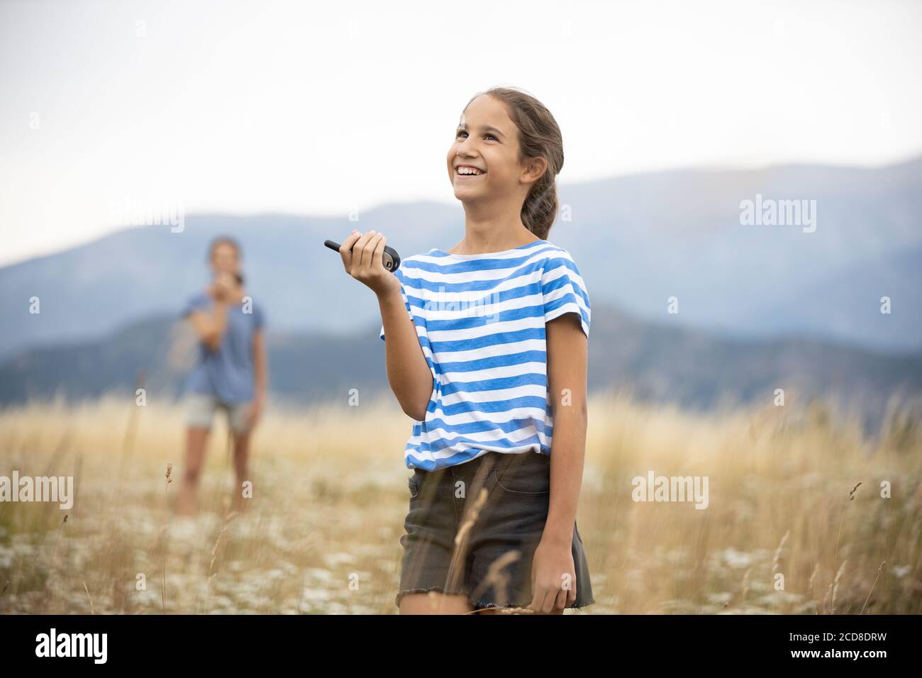 Zwei glückliche Mädchen spielen mit Walkie-Talkies in der Wiese Ein wundervolles Hotel Stockfoto