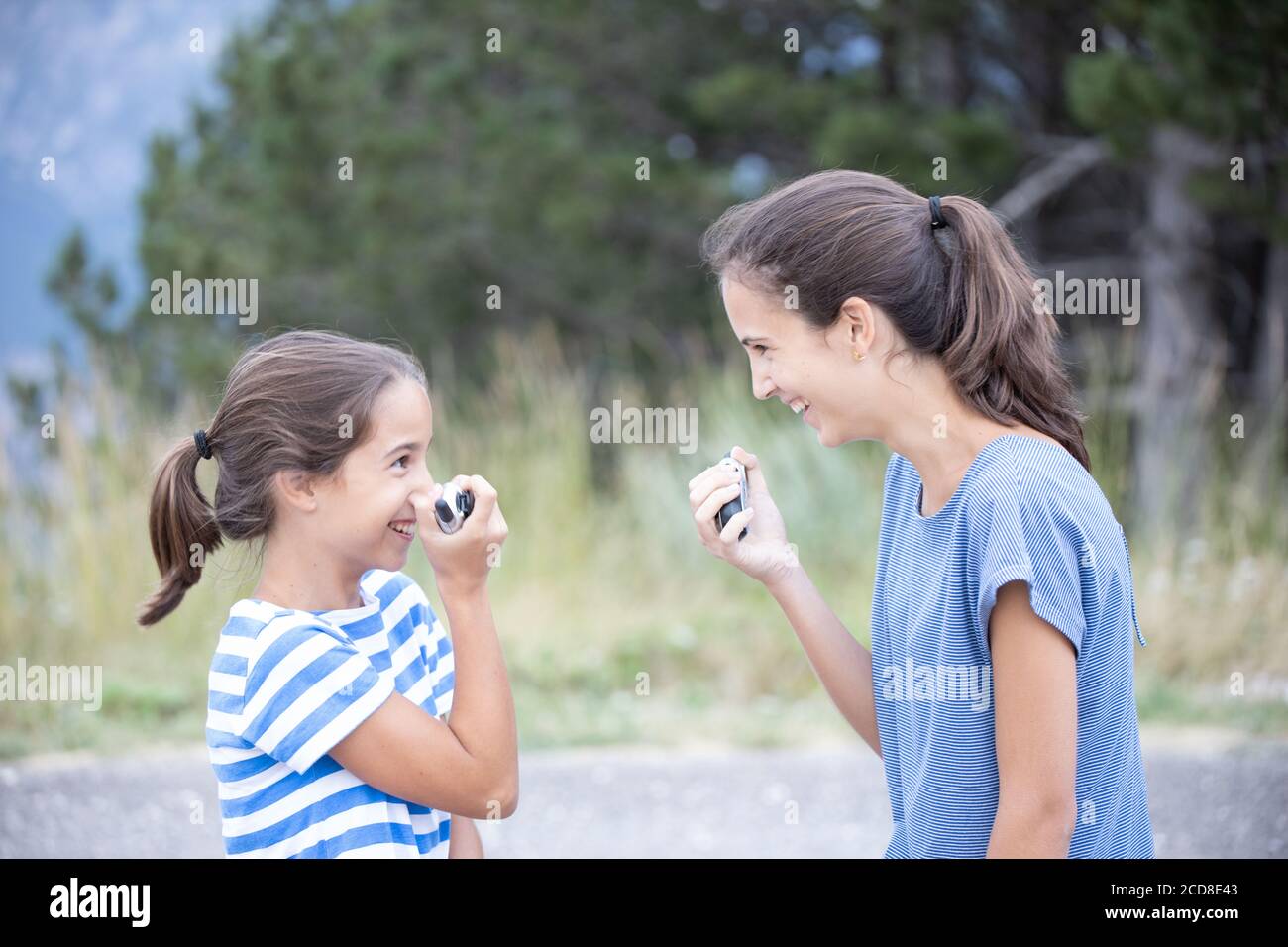 Zwei glückliche Schwestern sehr nahe reden und scherzen mit einem Walkie-Talkie Stockfoto