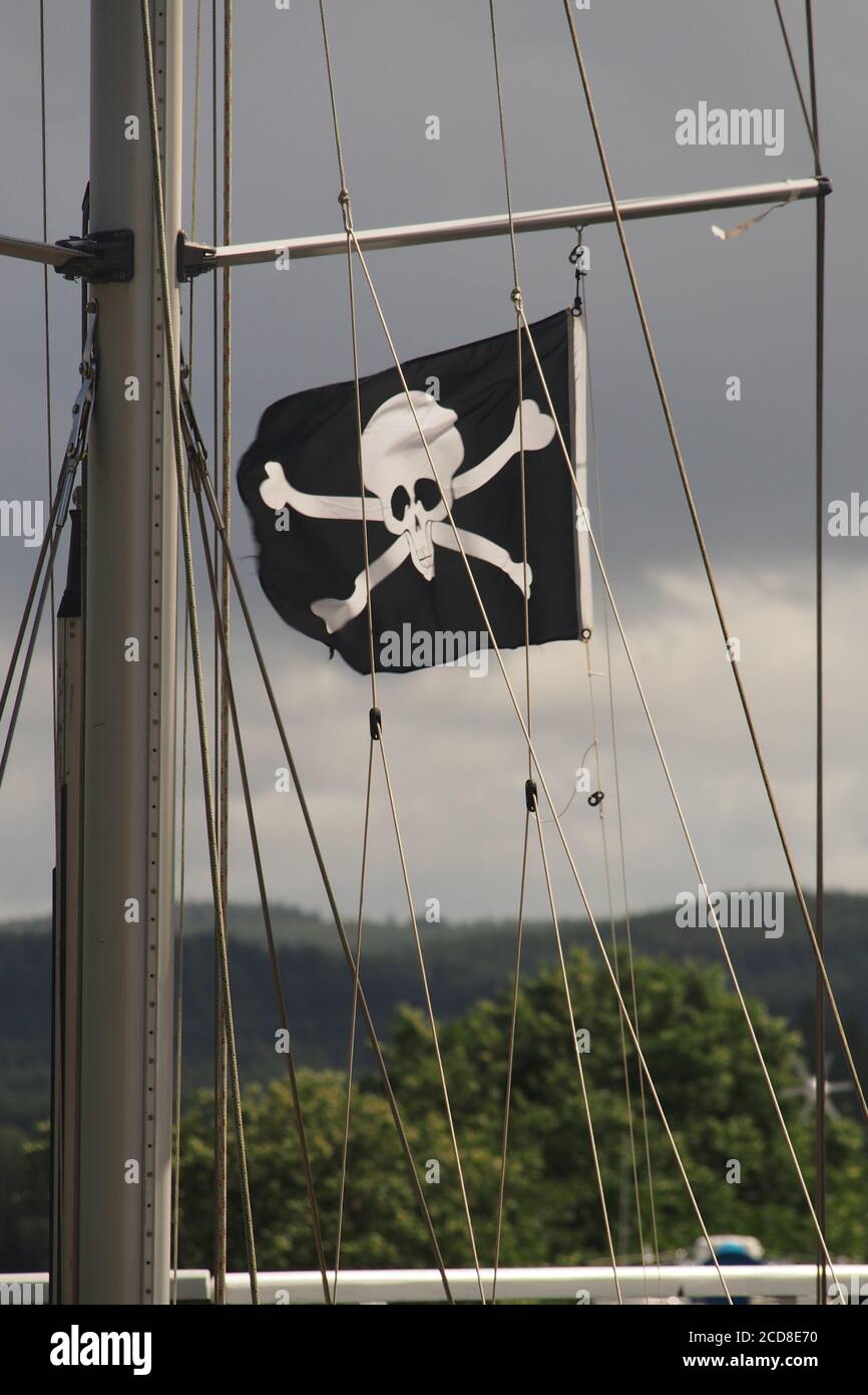 Ein Schädel und Kreuzknochen, der fröhliche roger, Flagge, die in der Takelage einer Yacht in einem Schloss auf dem Crinan Canal, Argyll, Schottland fliegt Stockfoto