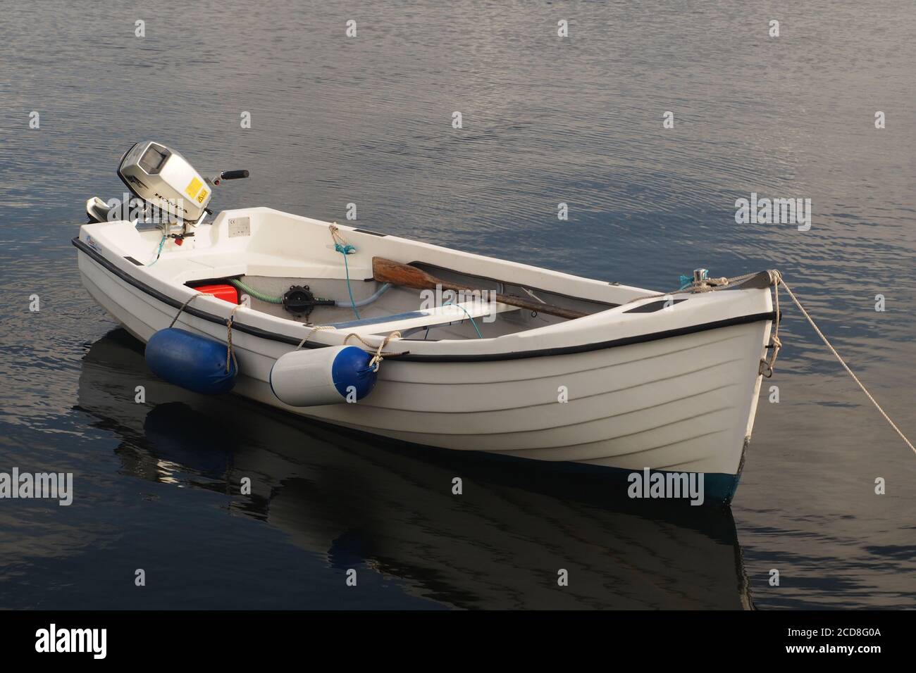 Ein weißes Ruderboot auch mit Außenbordmotor und Die Kotflügel liegen am Ardrishaig Pier auf ruhigem Wasser Stockfoto
