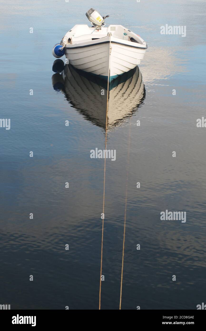 Ein weißes Ruderboot auch mit Außenbordmotor und Die Kotflügel liegen am Ardrishaig Pier auf ruhigem Wasser Stockfoto