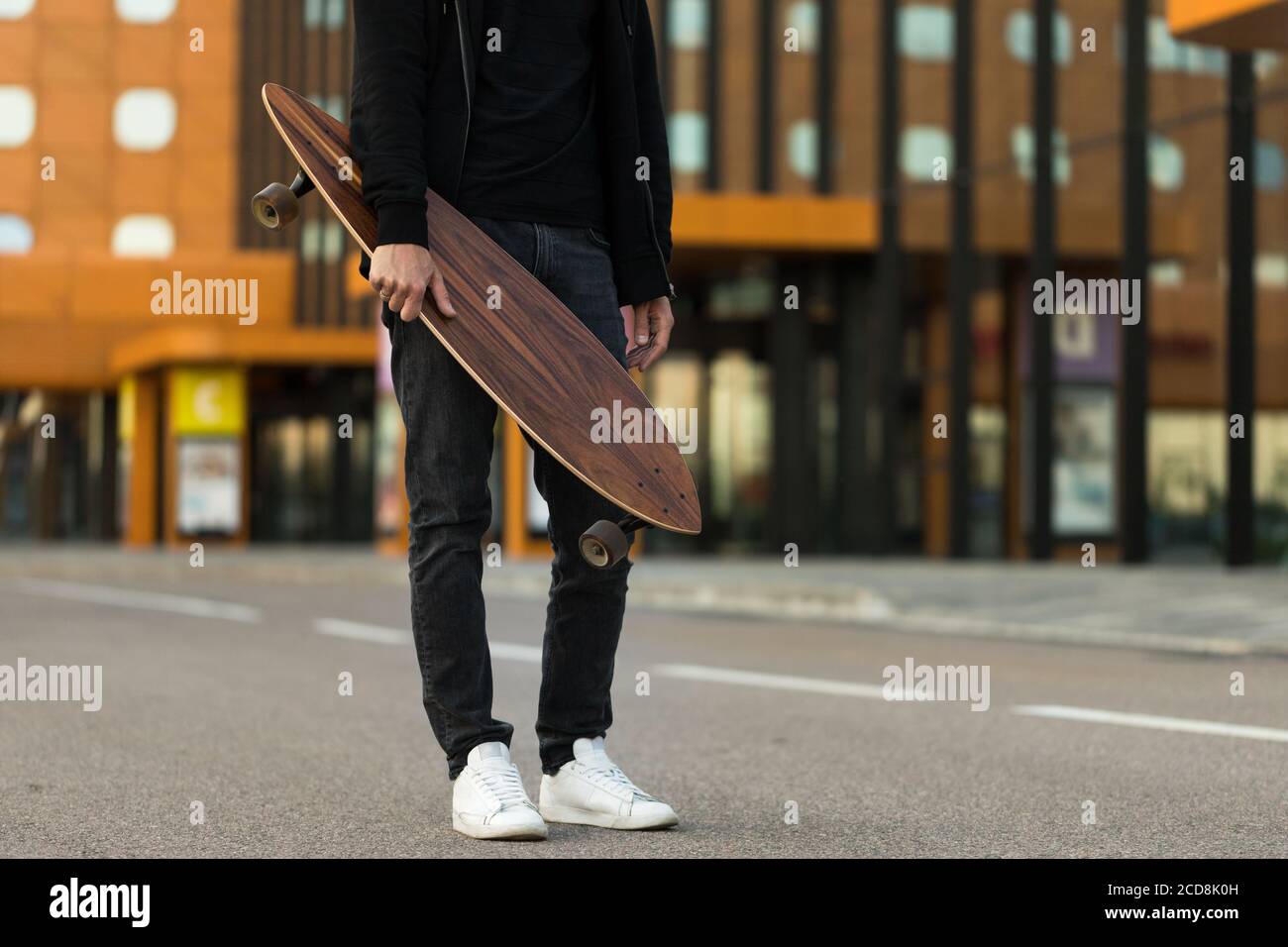 Mann Hipster hält Skateboard oder Long Board im Freien, zugeschnittenes Bild. Freizeit, gesunder Lebensstil, Extremsport Stockfoto