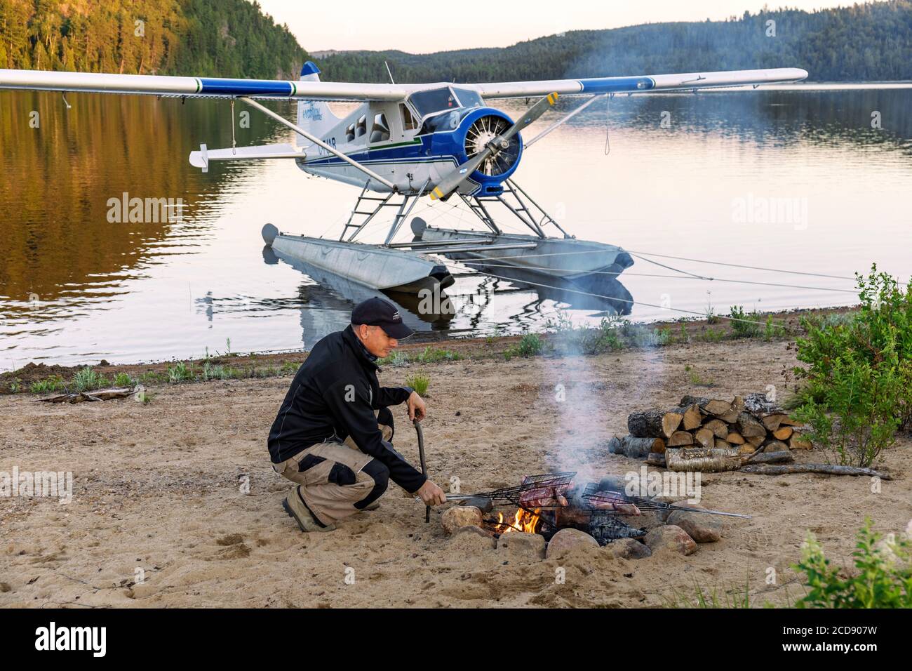 Kanada, Provinz Quebec, Mauricie Region, Hydravion Aventure, Saint-Maurice Wildlife Sanctuary nördlich des La Mauricie National Park, Familiencamp am Sandstrand am Lac Soucis, Pilot bereitet BBQ am Lagerfeuer vor Stockfoto