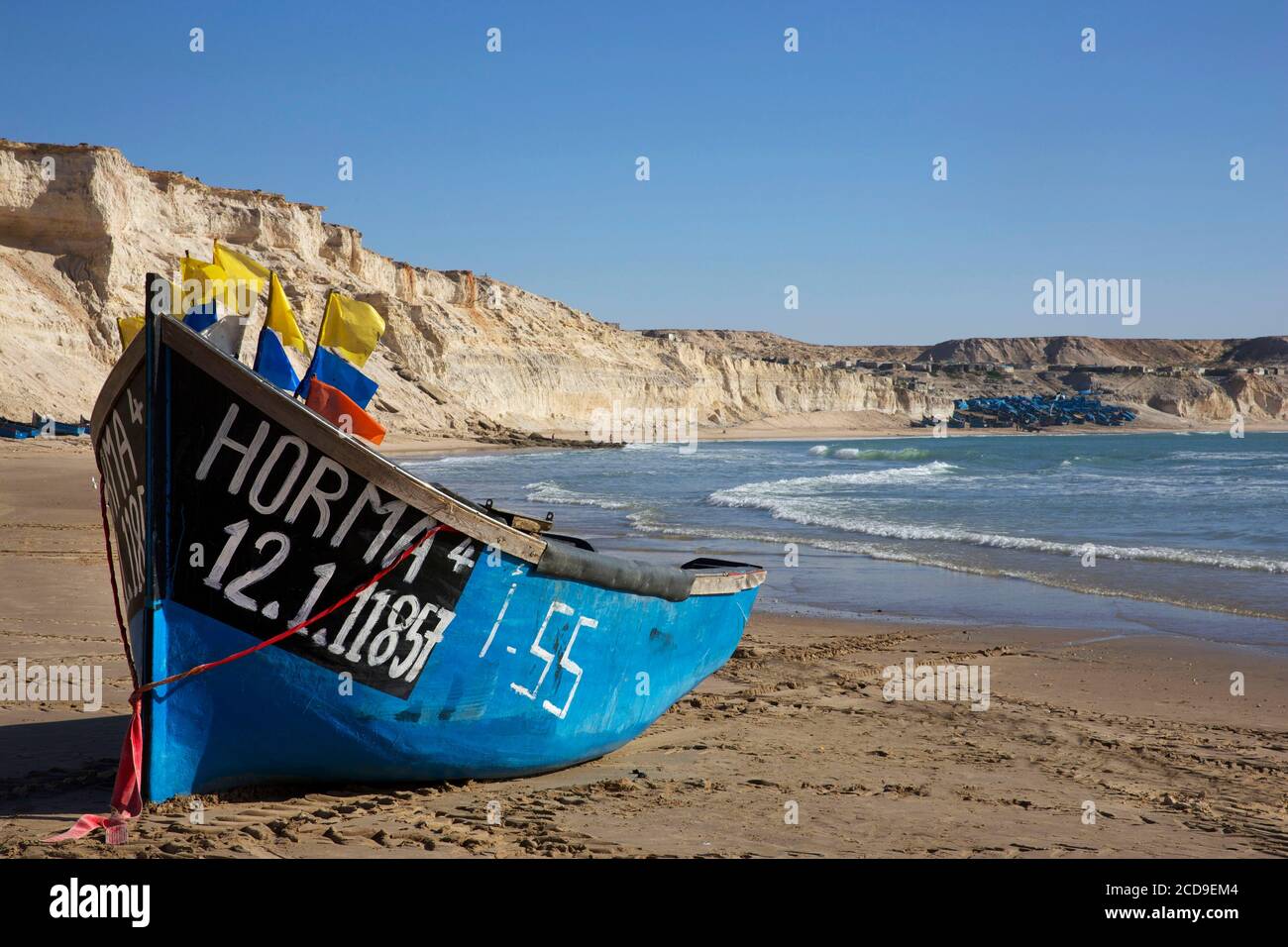 Marokko, Westsahara, Dakhla, blaues Fischerboot am Strand von Araiche, umgeben von einer Klippe Stockfoto