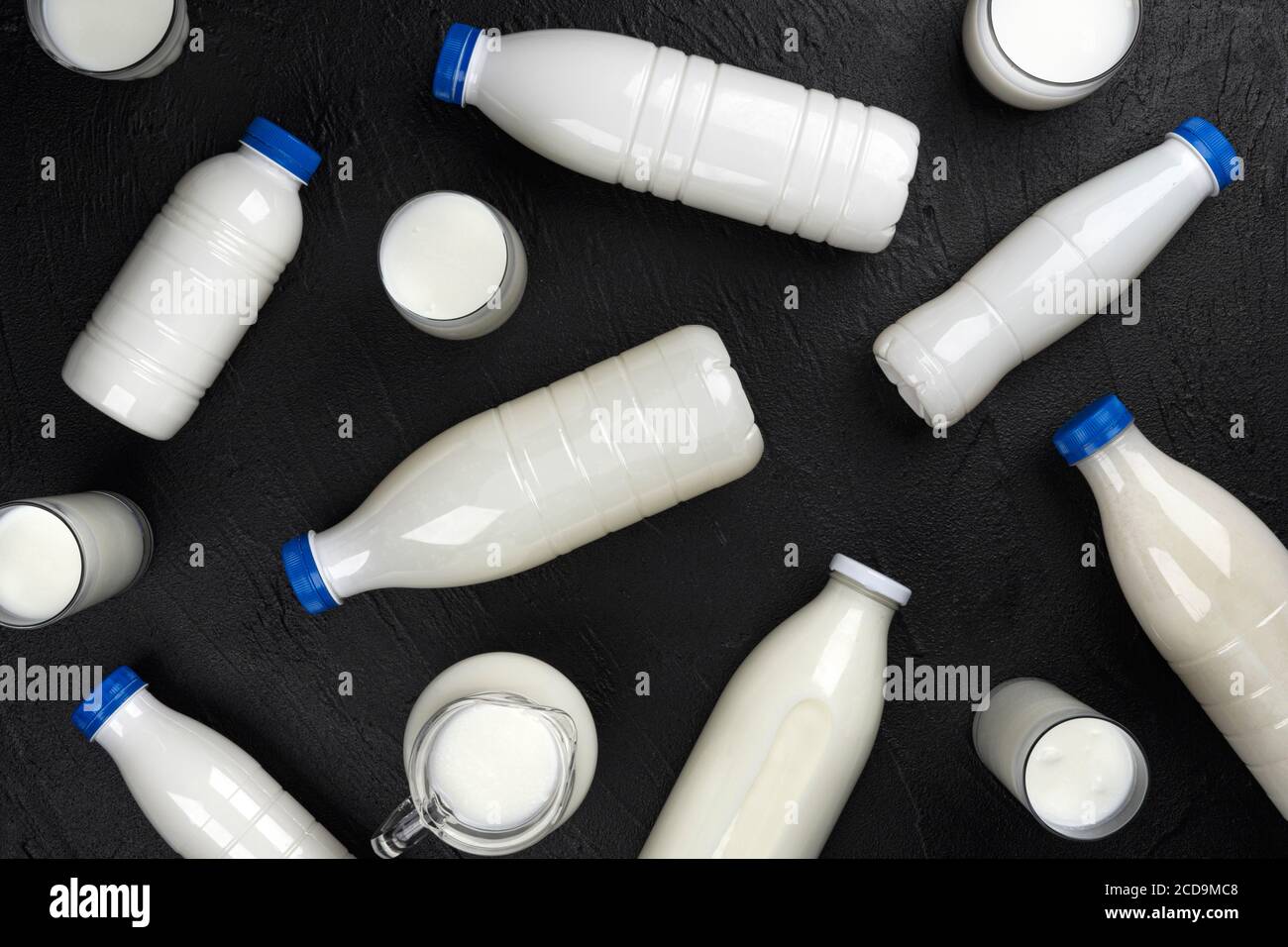 Milchprodukte Verpackung, Flaschen und Gläser mit Milch auf schwarzem Hintergrund, Draufsicht Stockfoto