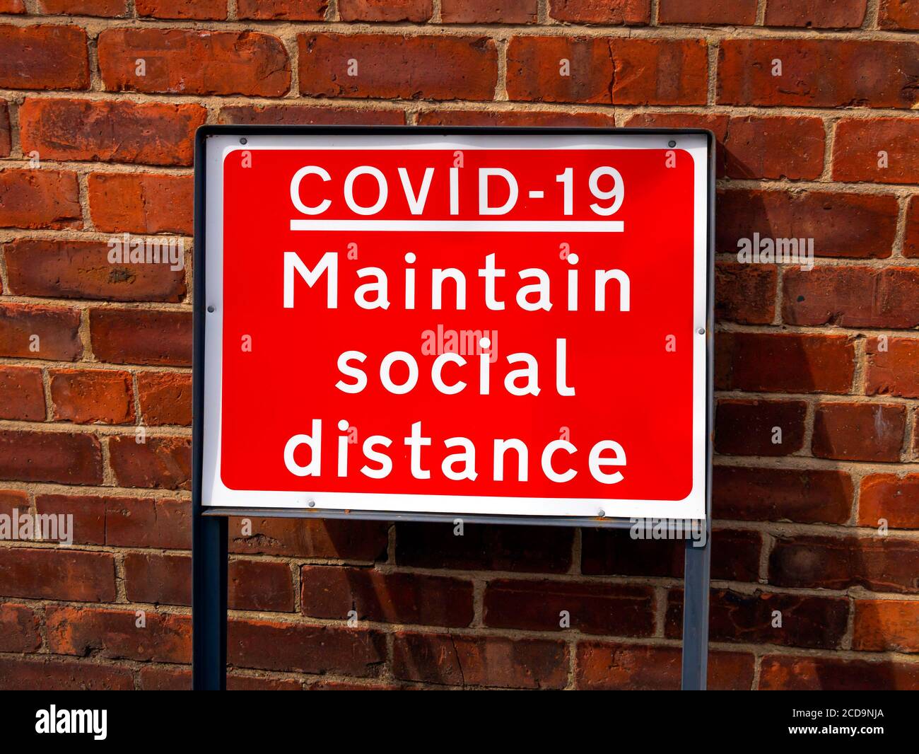 Ein rotes Straßenschild Covid 19 halten soziale Distanz Stockfoto