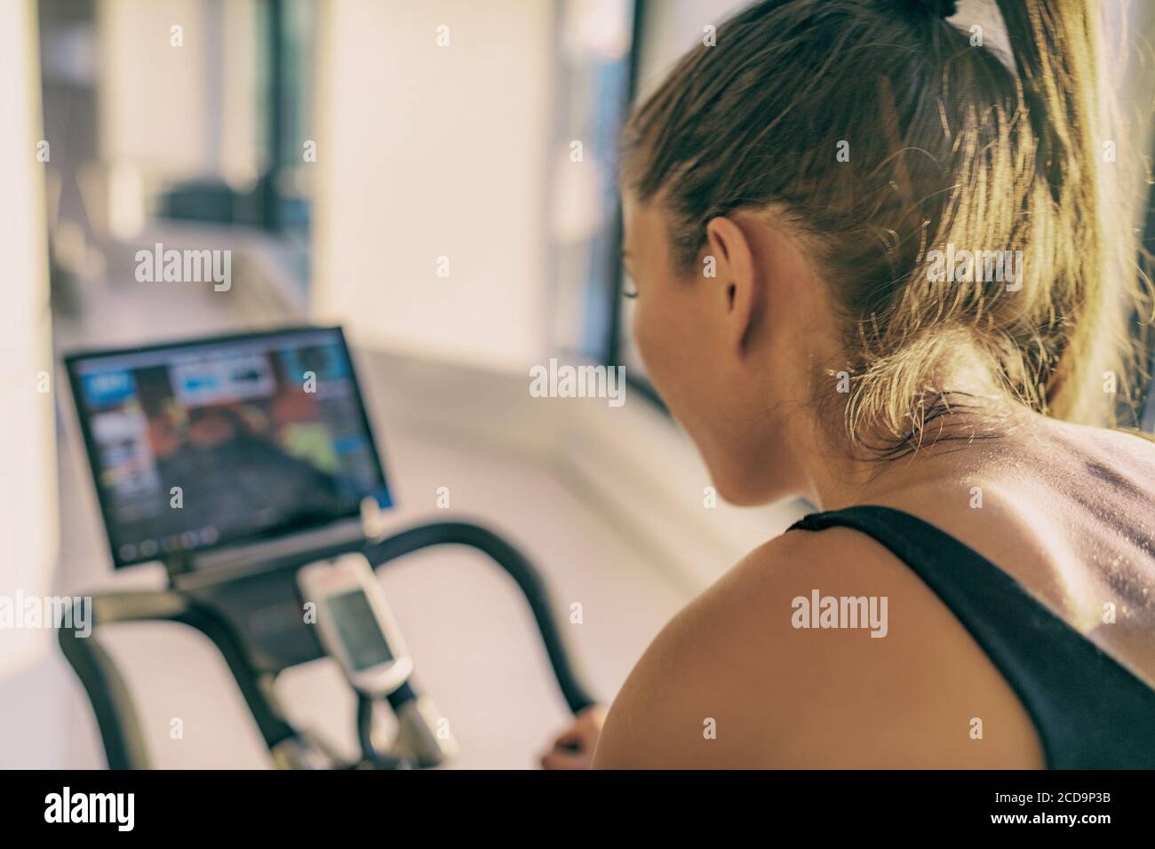 Smart Fitness-Home-Workout Radfahren Bildschirm mit Online-Klassen Frau Training auf stationären Fahrrad-Geräte in Innenräumen für Radfahren Übung. Indoor Cycling Stockfoto