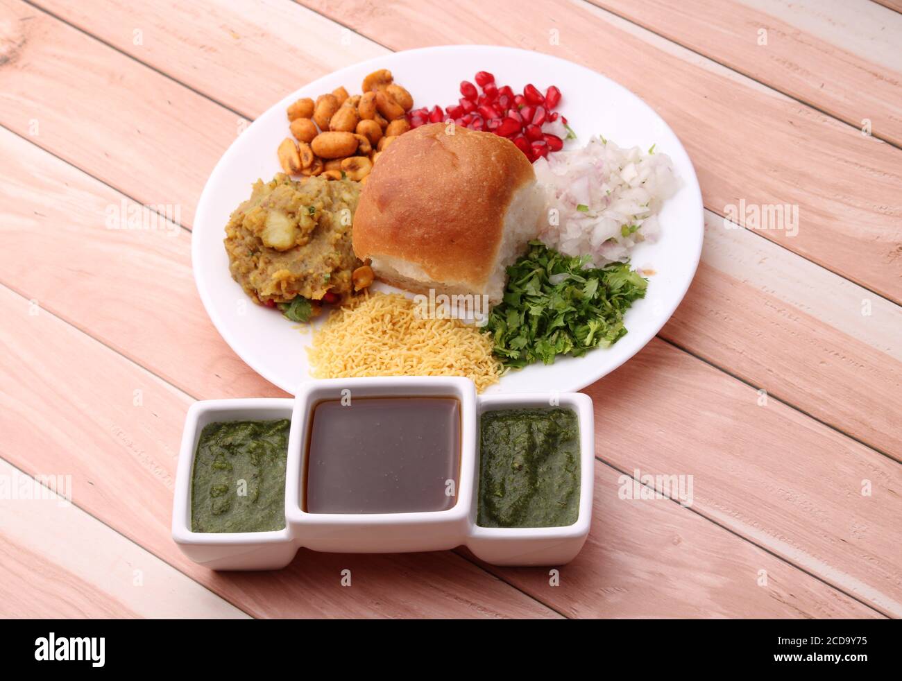 Dabeli ist ein indischer Snack mit Granatapfelkernen und Cilantro in weißer Keramikplatte. Mit grünem Chutney und Tamrinde Chutney. Stockfoto