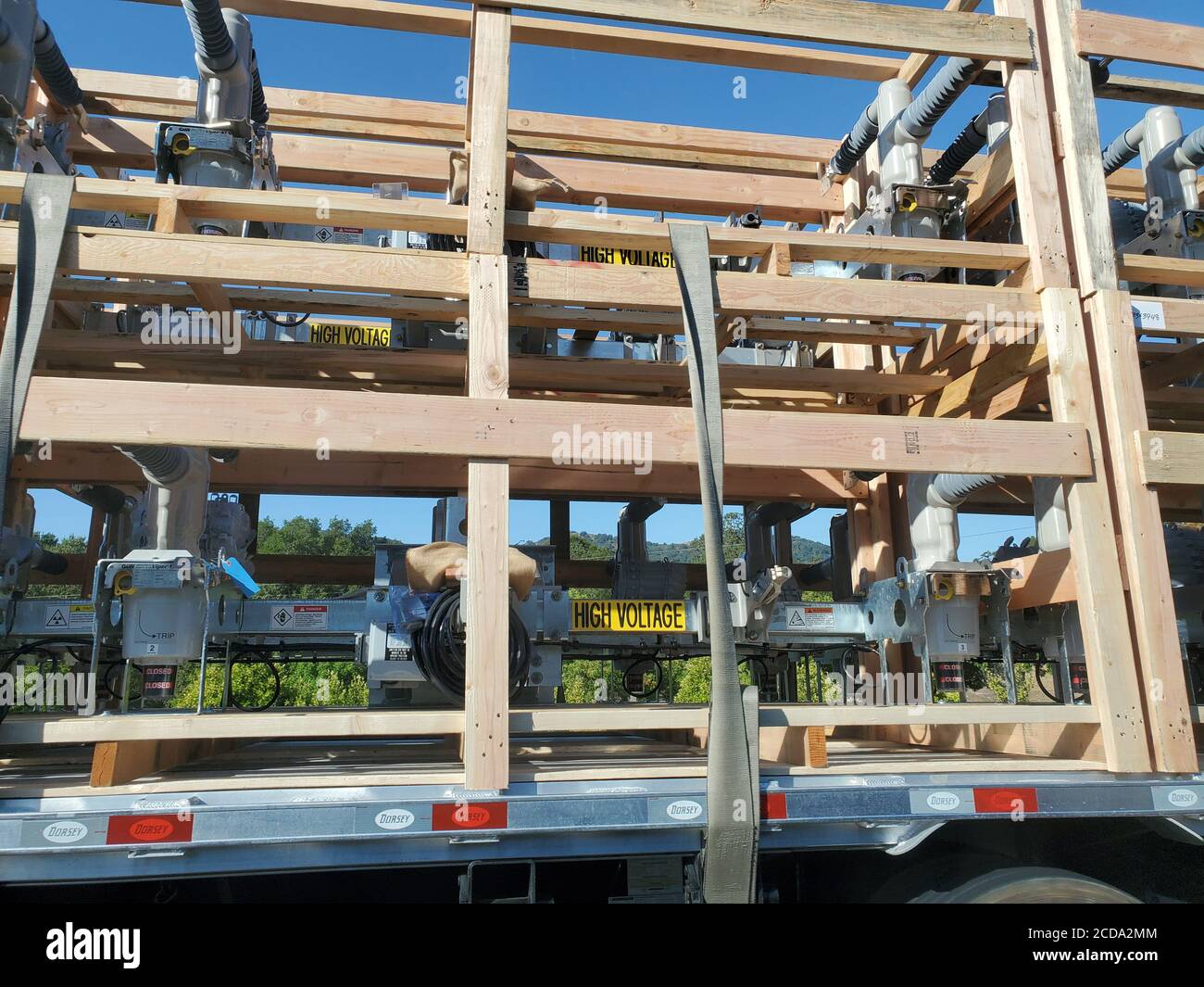 Nahaufnahme von offenen Holzkisten mit elektrischer Ausrüstung des Stromnetzes, mit Text mit der Aufschrift „Hochspannung“ auf der Rückseite eines Sattelwagens in Walnut Creek, Kalifornien, 10. August 2020. () Stockfoto