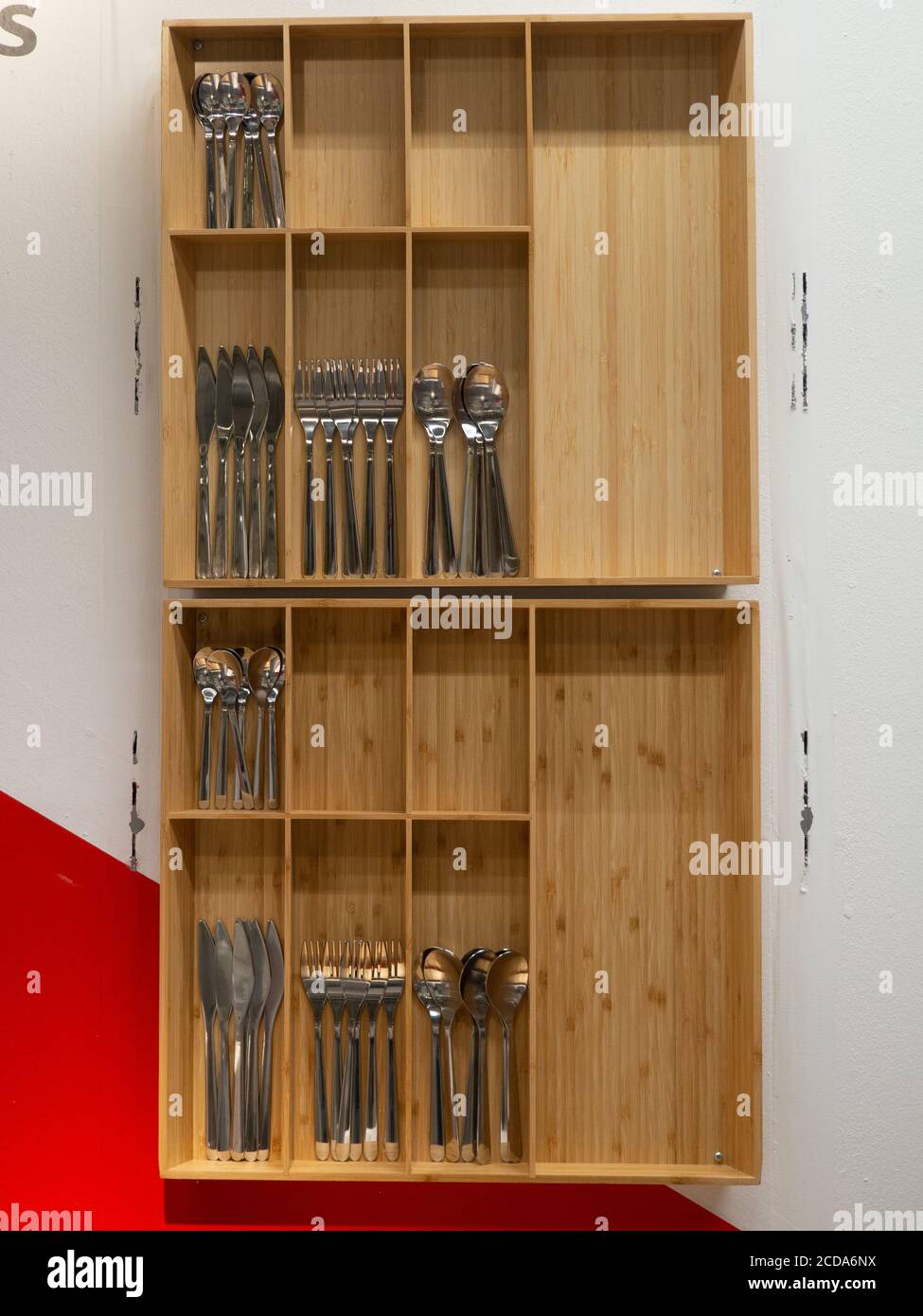 Vertikale Aufnahme des silbernen Sets von Gabeln, Messern und Löffeln im Holzregal Stockfoto