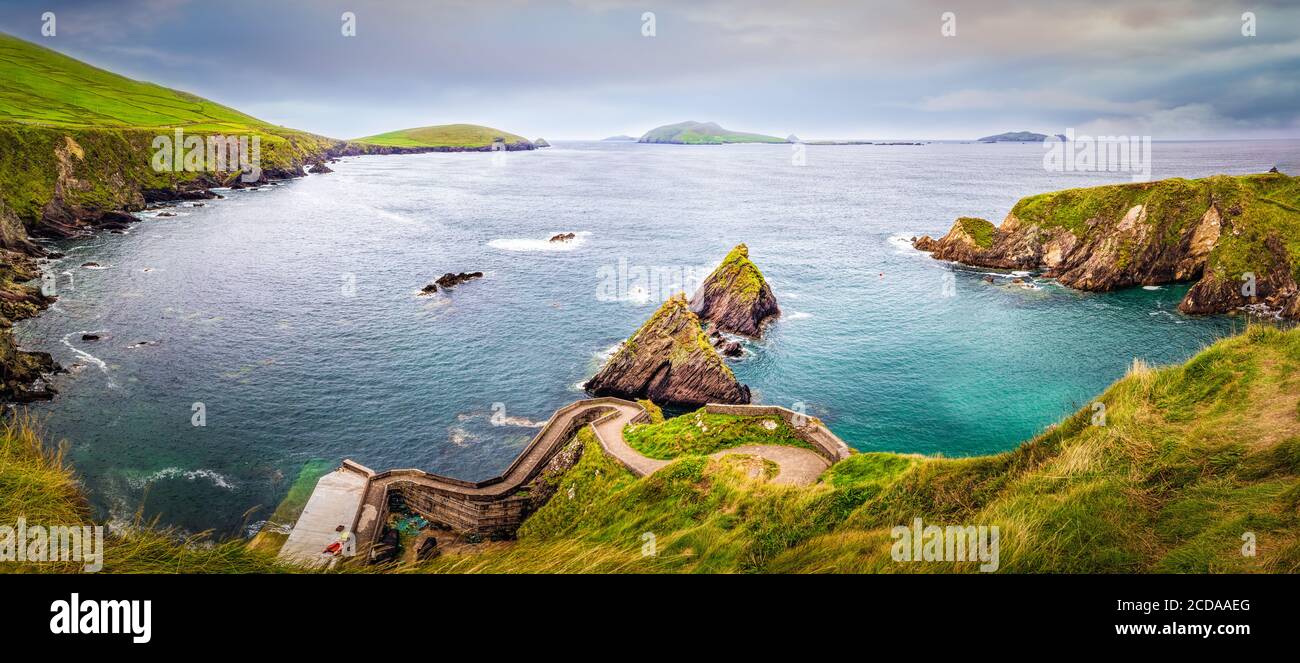 Schöne Aussicht auf Dunquin Hafen und kleine felsige Inseln mit türkisfarbenem Wasser und grünen Feldern im Hintergrund. Dingle Peninsula, Co Kerry, Irland Stockfoto