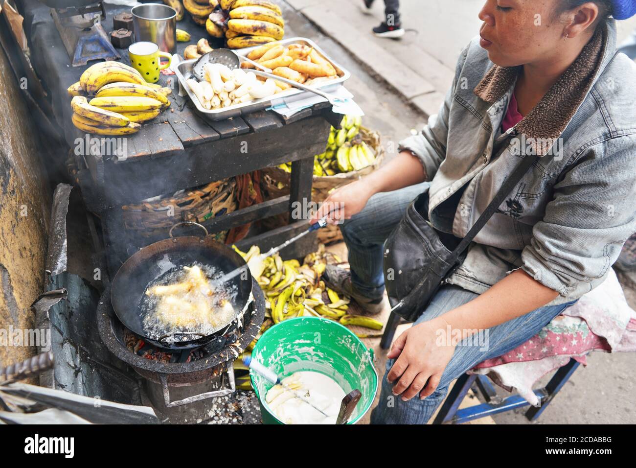 Antananarivo, Madagaskar - 24. April 2019: Lokale madagassische Frau, die Bananen in Öl an ihrem Stand auf dem Markt neben der Hauptstraße braten. Frisch zubereitetes Essen Stockfoto