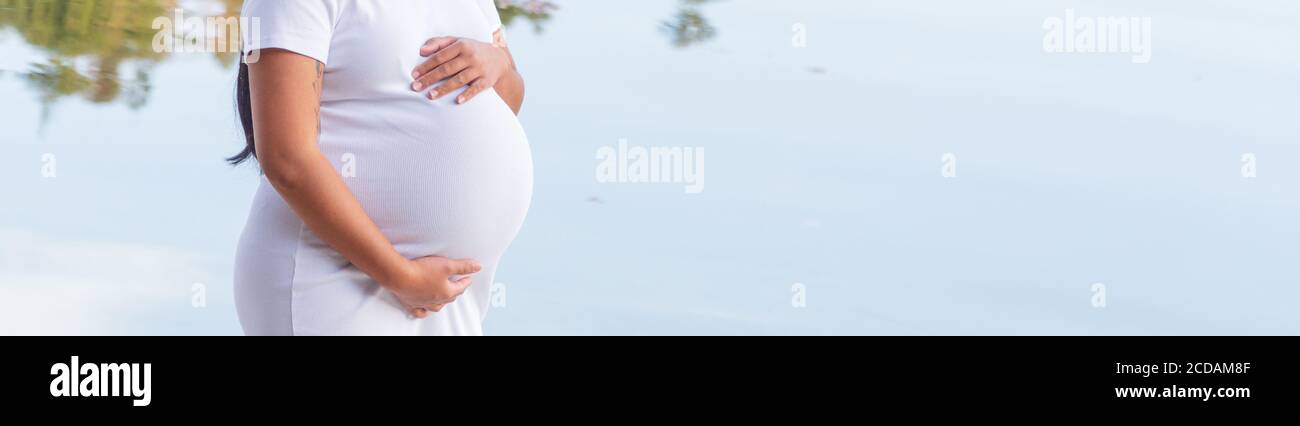 Schwangere asiatische Frau hält ihren Bauch Stockfoto