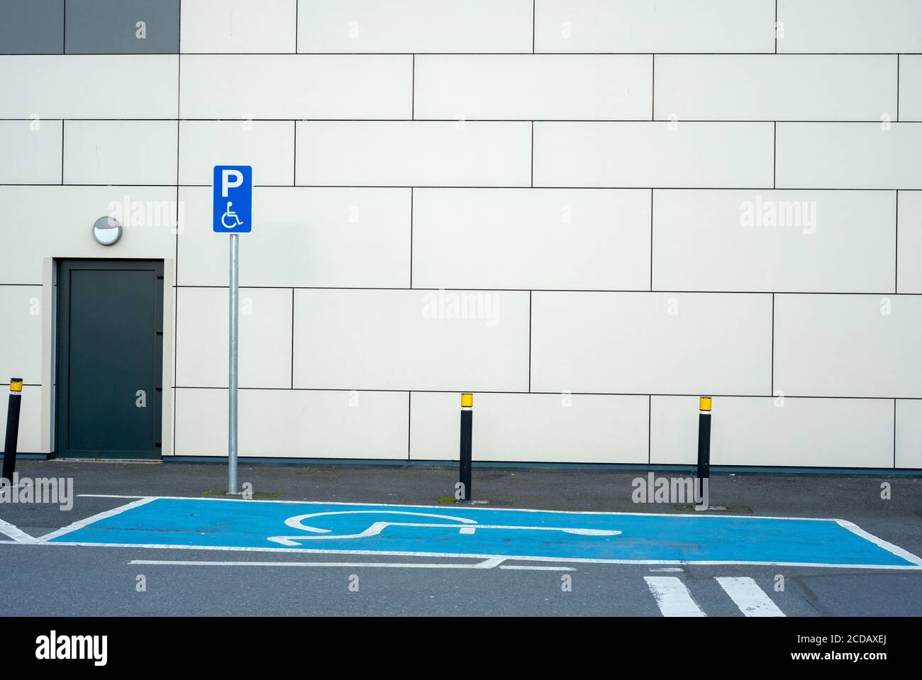 Leerer Behindertenparkplatz mit blauer Markierung und Behinderten-Schild an der Wand. Stockfoto