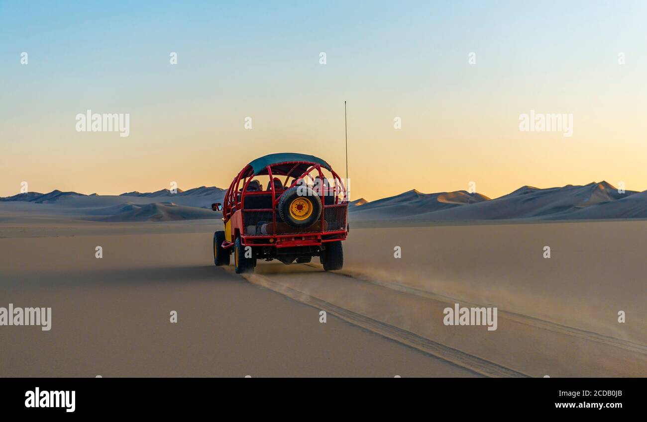 Wüstenbuggy, der bei Sonnenuntergang zwischen Ica und Huacachina, Peru, durch die Nazca-Wüste fährt. Stockfoto