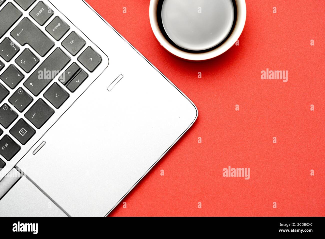 Draufsicht des Arbeitsplatzes auf rotem Hintergrund mit Laptop und Kaffee. Flach liegend Stockfoto