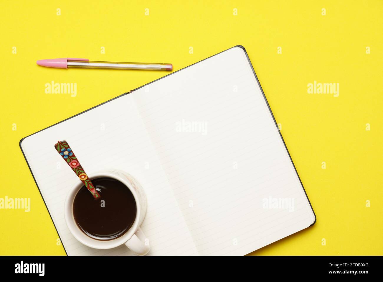 Arbeitsplatz mit Kaffeestift und Notizbuch auf gelbem Hintergrund. Flaches Design Stockfoto