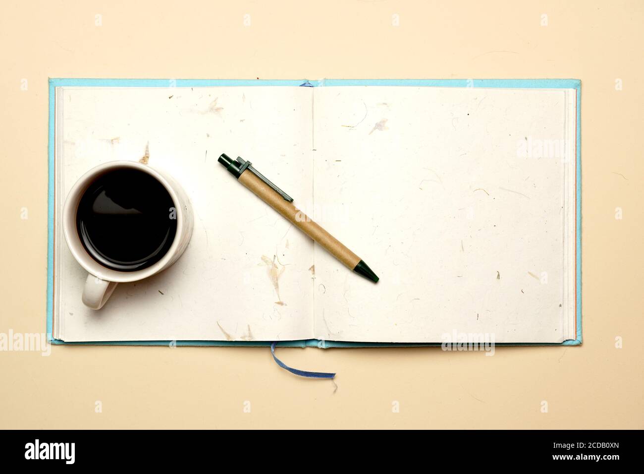 Arbeitsplatz mit Kaffeestift und Notizbuch auf gelbem Hintergrund. Flach liegend Stockfoto