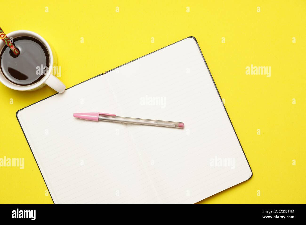 Arbeitsplatz mit Kaffeestift und Notizbuch auf gelbem Hintergrund. Flaches Design Stockfoto