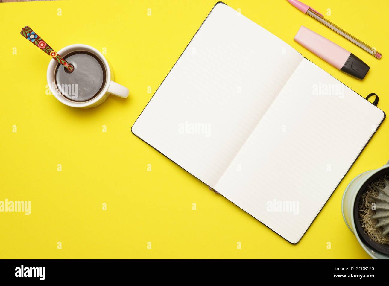 Arbeitsplatz mit Kaffeestift und Notizbuch auf gelbem Hintergrund. Flaches Design Stockfoto
