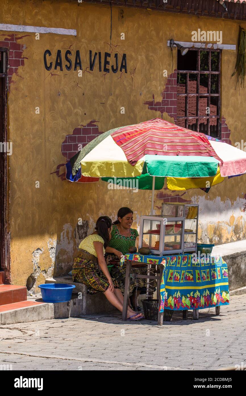 Tzutujil Maya Frauen in traditioneller Kleidung verkaufen Obst an einem Stand auf einer Straße in San Juan la Laguna, Guatemala. Stockfoto Tzutujil Maya Frauen in traditioneller Kleidung verkaufen Obst an einem Stand auf einer Straße in San Juan la Laguna, Guatemala. Stockfoto