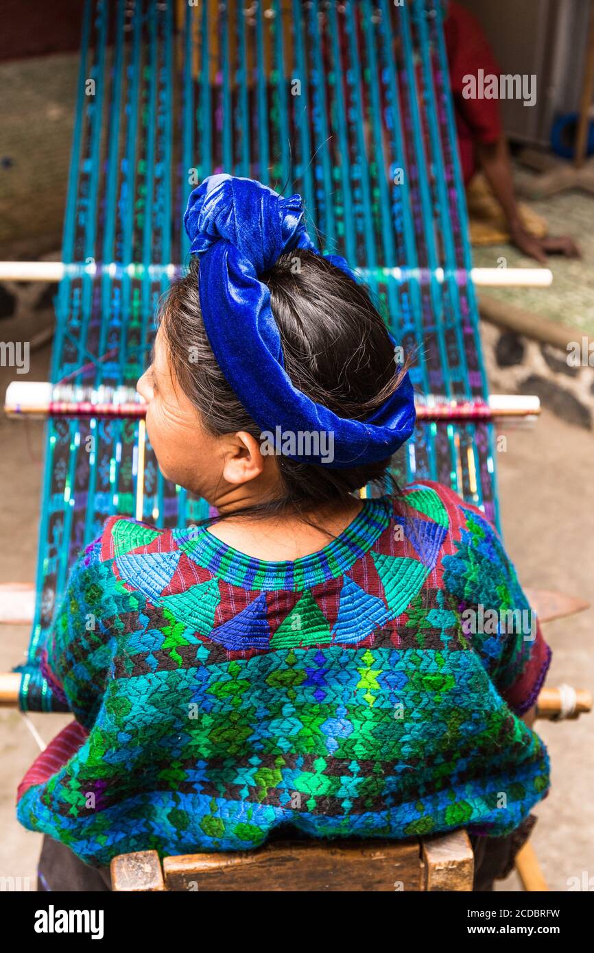 Ein Maya Frau in traditioneller Kleidung webt Stoff auf einem Webstuhl in Santa Cruz la Laguna, Guatemala. Stockfoto