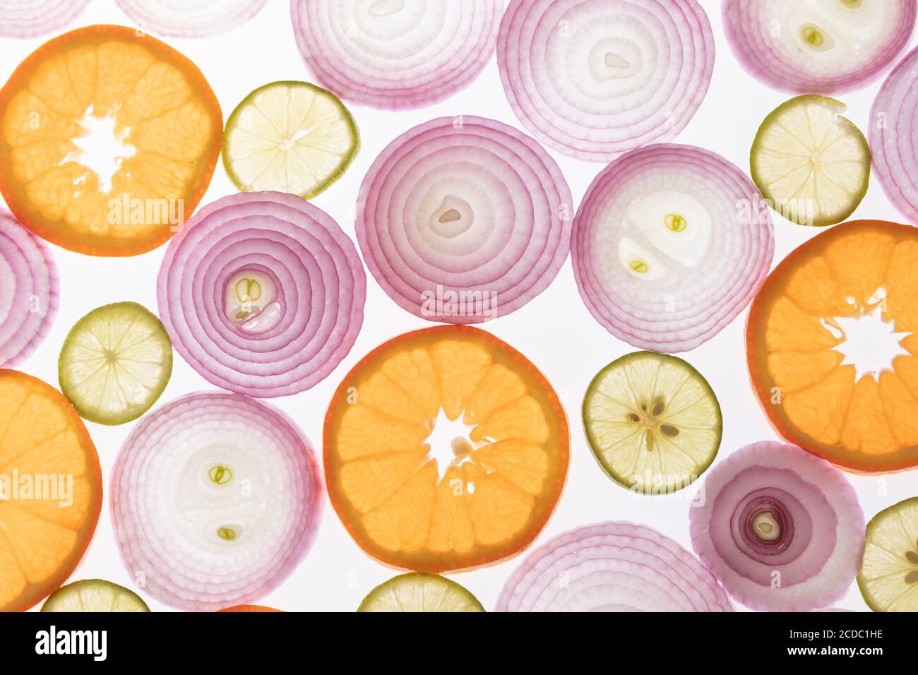 Zwiebeln, Zitronen und Orangen Hintergrund. Zwiebel, Zitronen und Orangen in Scheiben geschnitten. Hintergrundbeleuchtete Fotografie. Licht durchdringt die Elemente. Kombination von Farben. Stockfoto