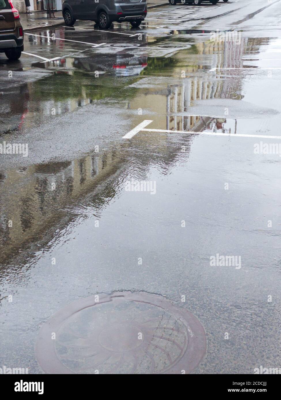 Autos auf einer nassen Straße nach heftigen Regenfällen in geparkt Innenstadt Stockfoto