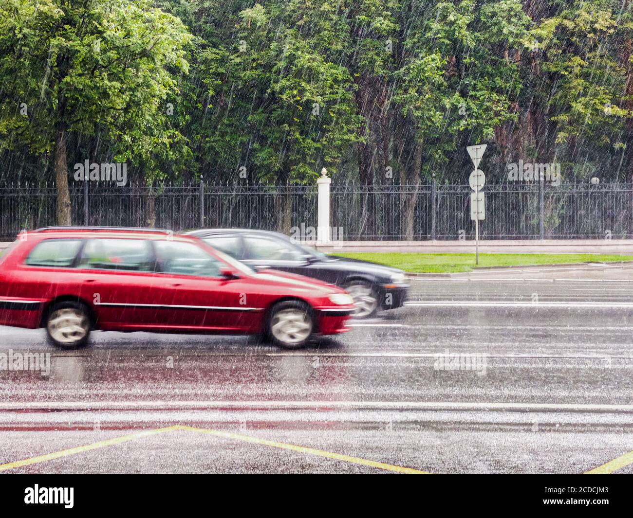 Fahren bei regnerischem Wetter. Autos gehen durch die überflutete Straße bei extrem starken Regenfällen Stockfoto