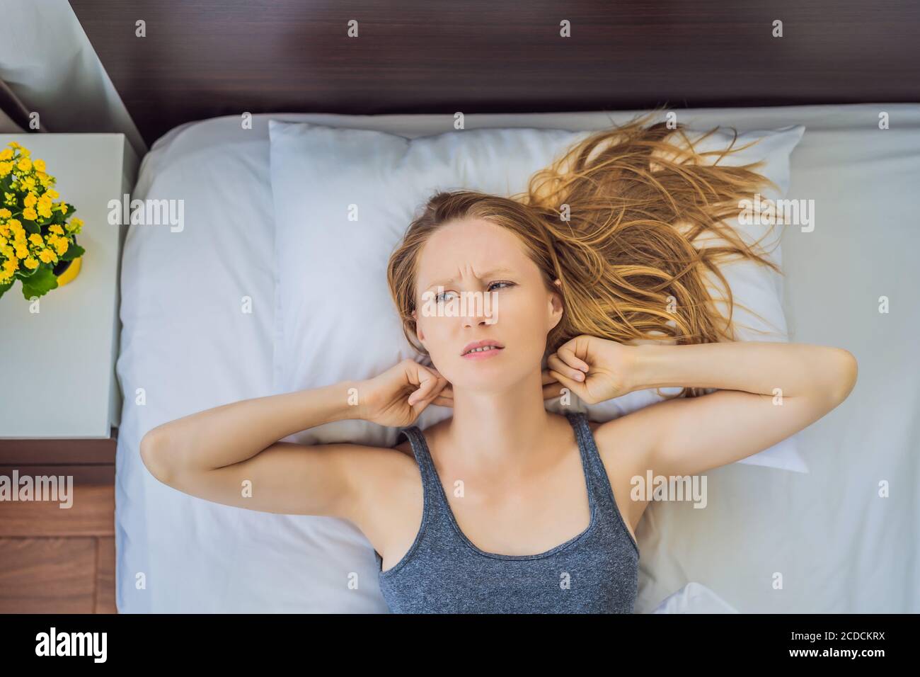 Verärgert junge Frau im Bett liegend am Morgen fühlt Schmerzen im Nacken nach dem Nachtschlaf, erwachen mit schmerzhaften plötzlichen Schmerzen oder Steifheit, falsche Haltung Stockfoto