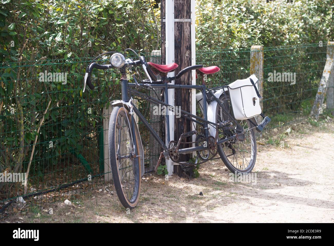 Altes Vintage Tandemrad gegen einen hölzernen elektrischen Pol. Zwei weiße Fahrradtaschen. Stockfoto