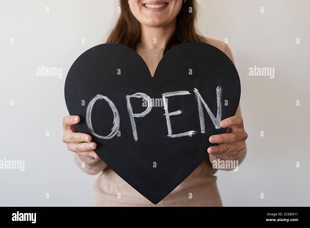 Frau mit OFFENEM herzförmigen Zeichen. Wiedereröffnung lokaler Unternehmen Stockfoto