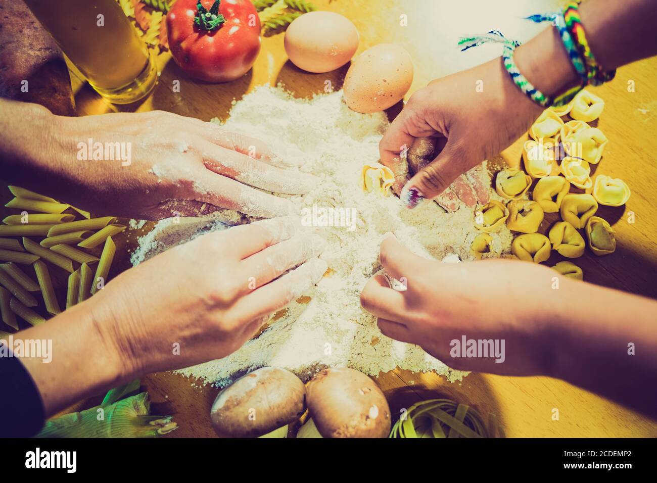Familie Kochen hausgemachte Pasta, Mamas Hände und Tochter in Mehl auf einem Holztisch Hintergrund. Verschiedene Pasta mit Gemüse und Eiern - Bild Stockfoto