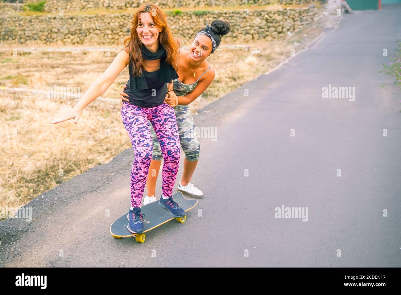 Junge Mutter übt auf Skateboard auf der Straße. Tochter hilft Mama auf  Skateboard. Mama lernen, Skateboard fahren, wie Tochter lehrt sie in th  Stockfotografie - Alamy
