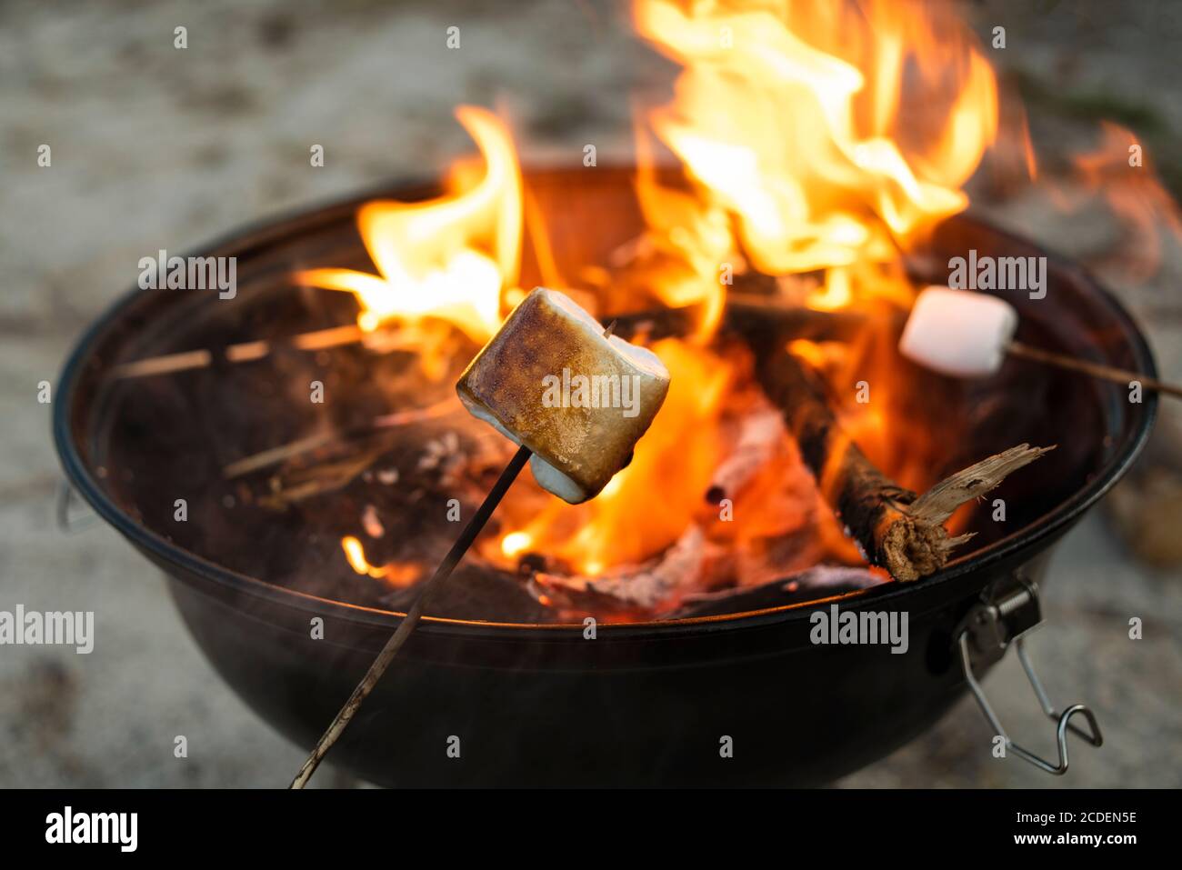 Geröstete Marshmallow auf hölzernen Stock in der Nähe der Feuerstelle. Stockfoto