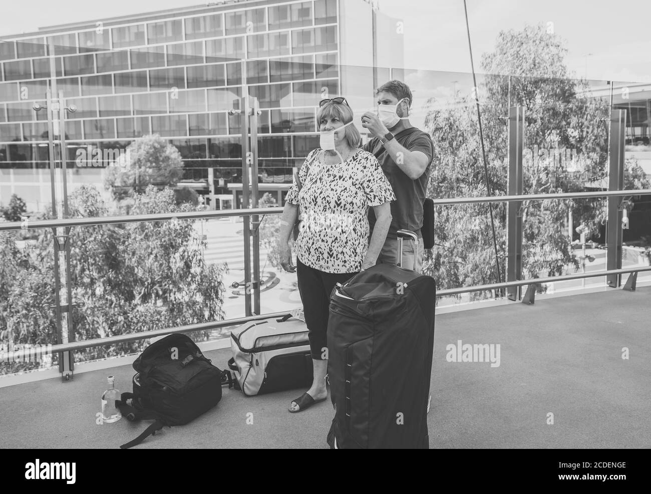 COVID-19 Reisen in der neuen Normalität. Sohn und ältere Mutter mit schützender Gesichtsmaske auf dem Flughafen Reisen zurück Heimatland besorgt über Coronavirus q Stockfoto