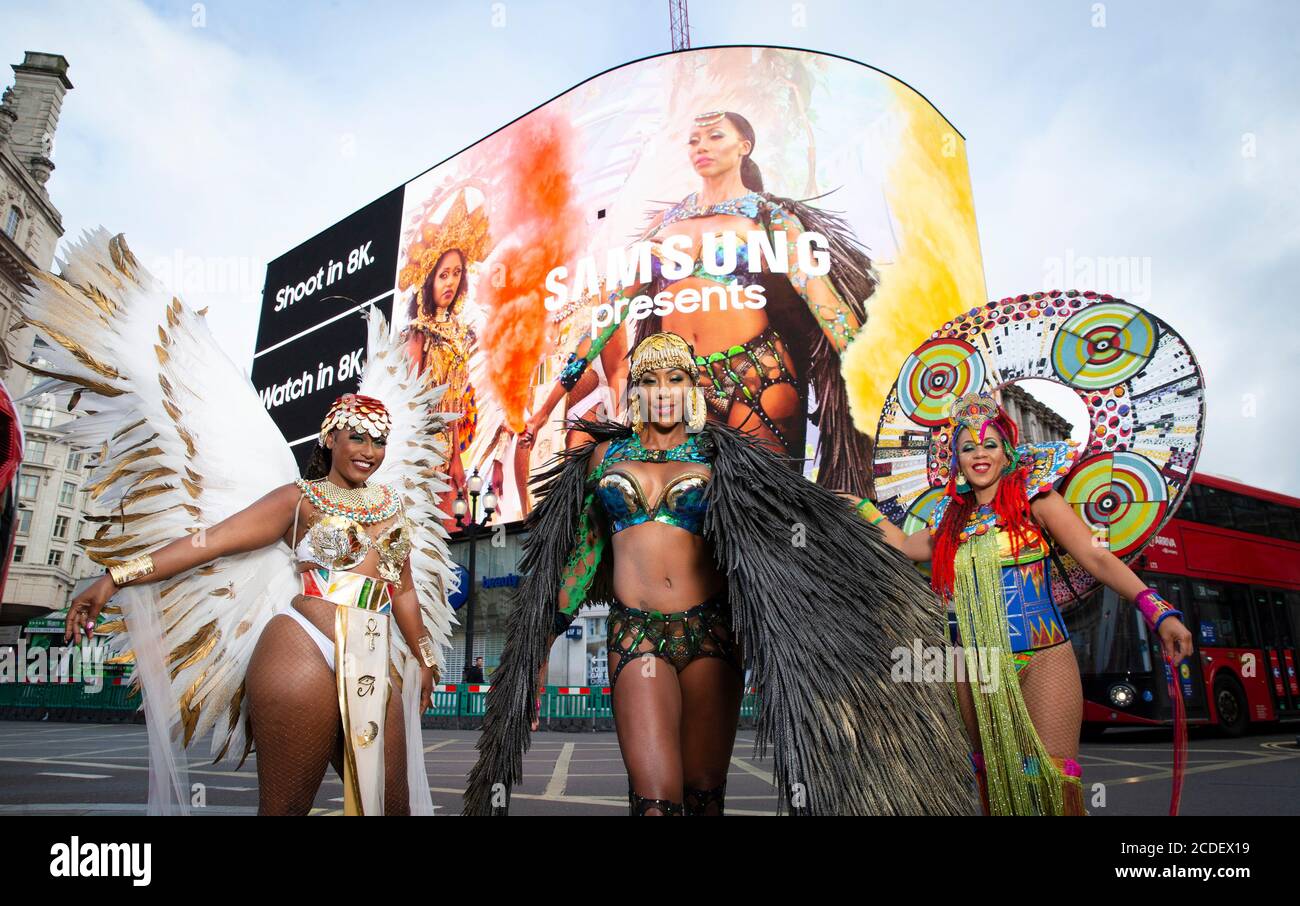 Ein Trio karibischer Soca-Tänzer, Donna Cupid-Tuesday, Andrea Wallace und Fiona Compton, unterhalten Passanten, während Samsung auf dem Piccadilly Circus einen Trailer zum ersten digitalen Notting Hill Carnival in London enthüllen wird. Stockfoto