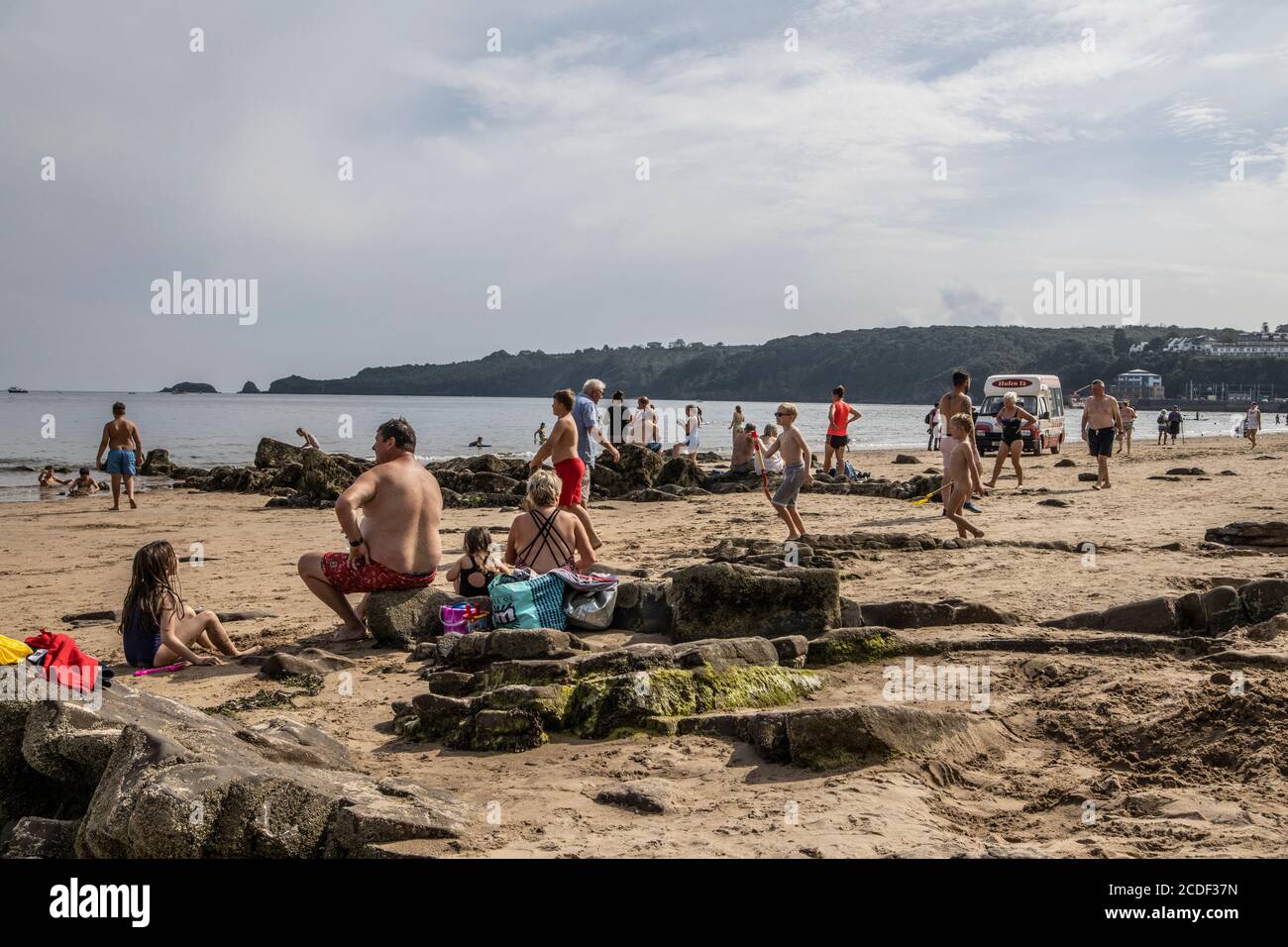 Menschen, die das warme Wetter am Coppet Hall Beach, Saundersfoot Bay, Pembrokeshire, West Wales, Großbritannien genießen Stockfoto