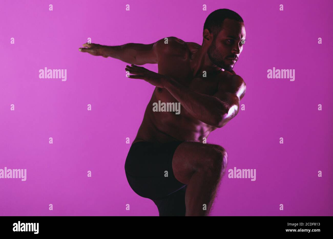 Fokussierter Sportler beim Fitnesstraining. Monochrome Fitness-Porträt von sportlichen Mann arbeiten auf lila Hintergrund. Stockfoto