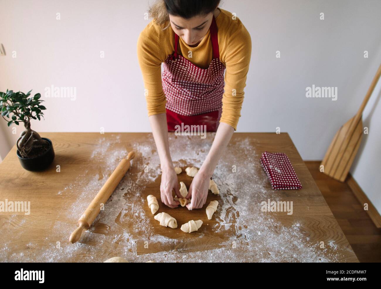 Frau trägt Schürze Vorbereitung Brötchen Teig zum Backen Stockfoto